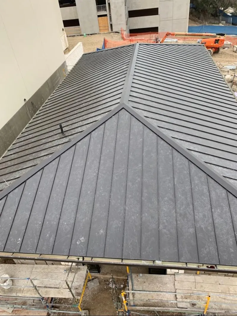 Commercial metal roof construction with crane equipment in Colton